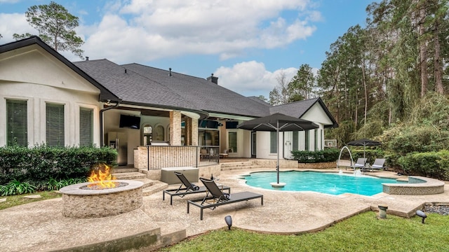 view of pool with pool water feature, a patio, and a fire pit