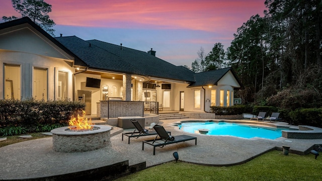 pool at dusk with a patio and a fire pit