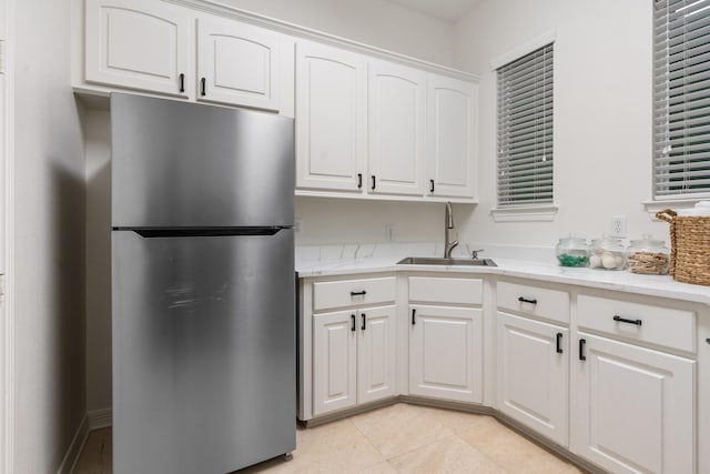 kitchen featuring white cabinetry, stainless steel fridge, sink, and light tile patterned flooring