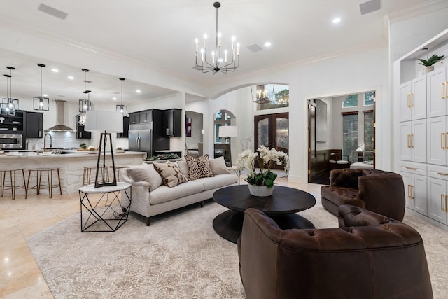 living room with french doors, an inviting chandelier, ornamental molding, and sink