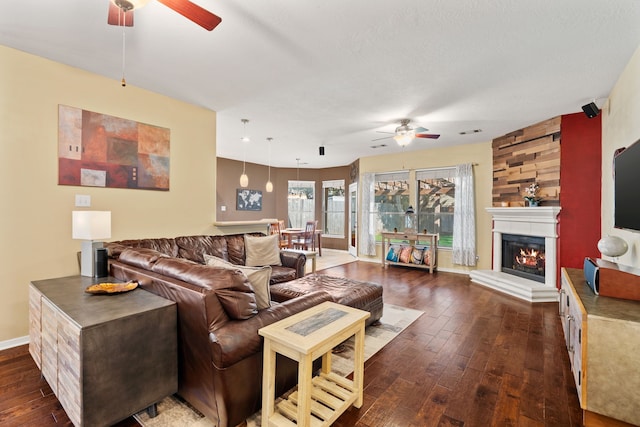 living room featuring ceiling fan, dark hardwood / wood-style floors, wood walls, and a fireplace