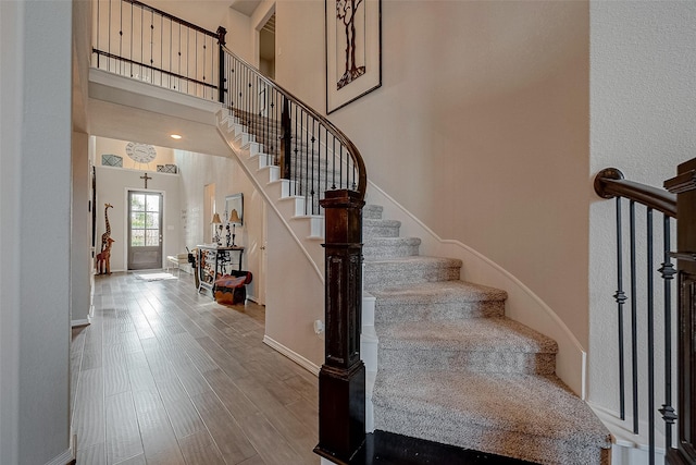 stairs with a towering ceiling and hardwood / wood-style flooring