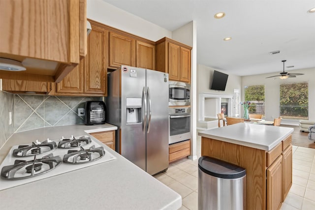 kitchen with visible vents, a center island, stainless steel appliances, light countertops, and backsplash