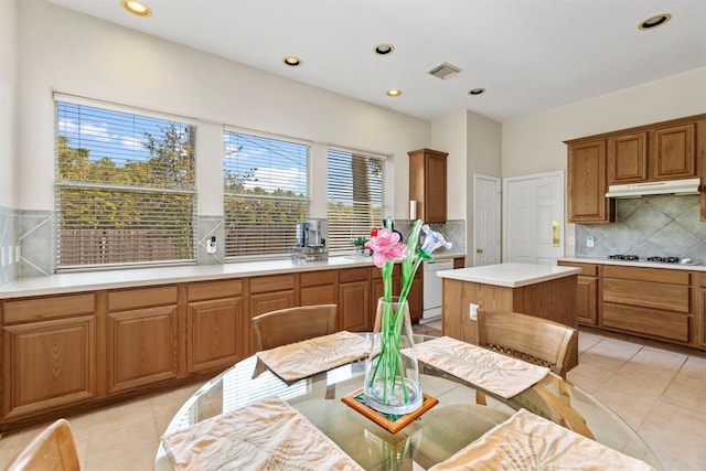 kitchen featuring brown cabinetry, light countertops, dishwasher, and under cabinet range hood