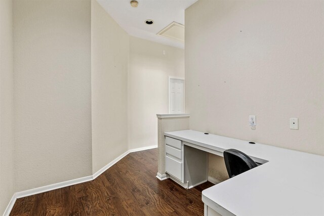 unfurnished office featuring built in desk, baseboards, and dark wood-style flooring