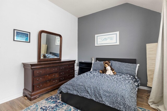 bedroom with lofted ceiling, baseboards, and wood finished floors