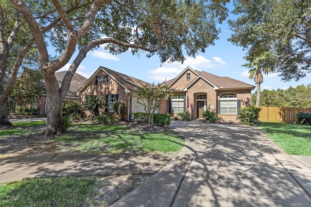 view of front facade with driveway, an attached garage, fence, and brick siding