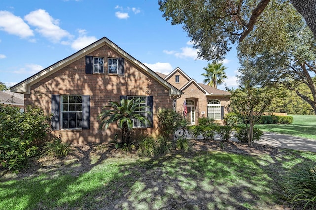 traditional-style home with brick siding and a front lawn