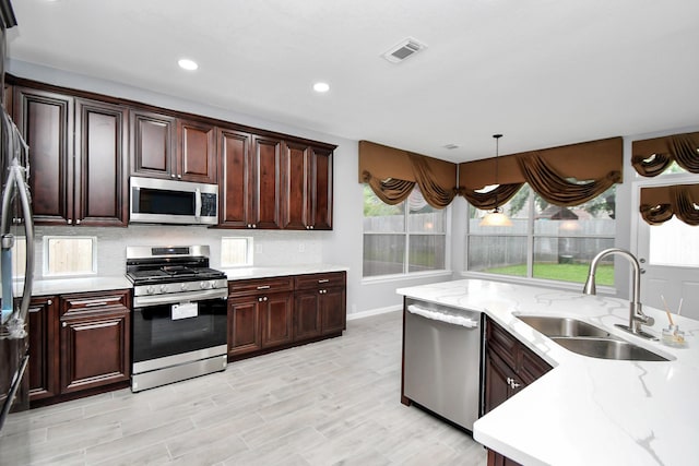 kitchen with pendant lighting, a healthy amount of sunlight, sink, and appliances with stainless steel finishes