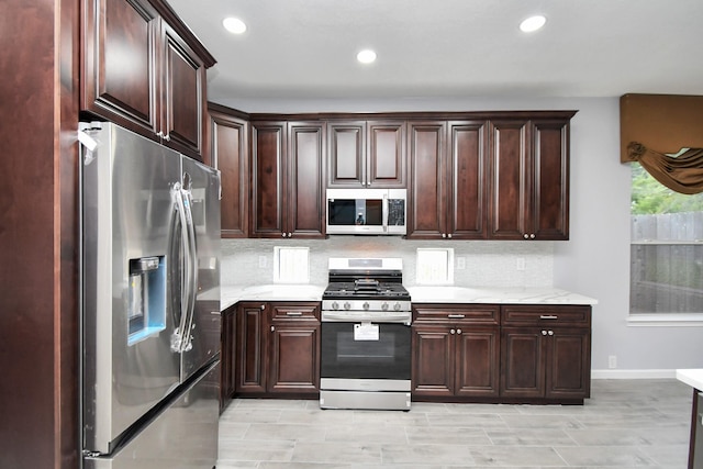 kitchen with light stone countertops, backsplash, dark brown cabinetry, range with gas cooktop, and stainless steel fridge with ice dispenser