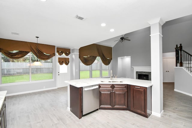 kitchen with ceiling fan, dishwasher, sink, light stone counters, and light hardwood / wood-style flooring