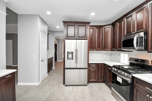 kitchen with dark brown cabinets, backsplash, stainless steel appliances, and light hardwood / wood-style flooring