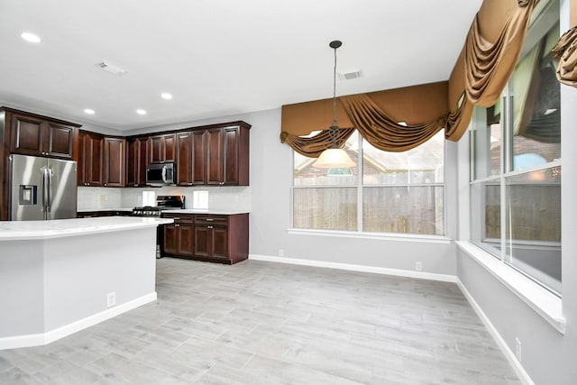 kitchen with backsplash, dark brown cabinetry, hanging light fixtures, and appliances with stainless steel finishes