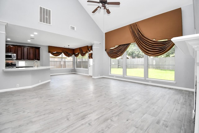 unfurnished living room featuring ceiling fan, light hardwood / wood-style flooring, high vaulted ceiling, and sink