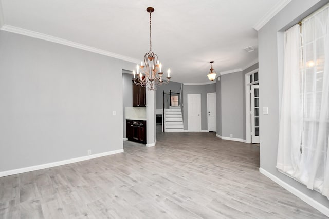 unfurnished living room featuring light wood-type flooring, an inviting chandelier, a barn door, and ornamental molding