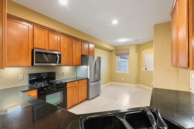 kitchen featuring dark stone countertops, decorative backsplash, sink, light tile patterned flooring, and stainless steel appliances