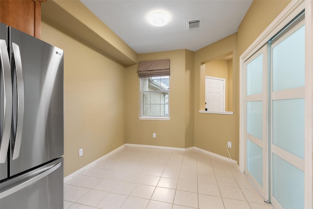 interior space with light tile patterned floors and stainless steel refrigerator