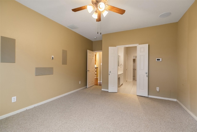 unfurnished bedroom featuring ceiling fan, light colored carpet, and ensuite bath