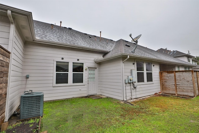 rear view of property with central AC and a lawn