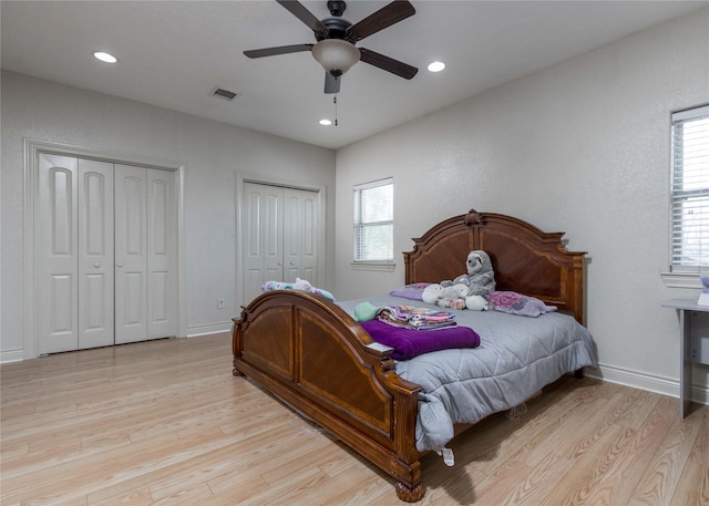 bedroom featuring multiple closets, ceiling fan, and light hardwood / wood-style flooring