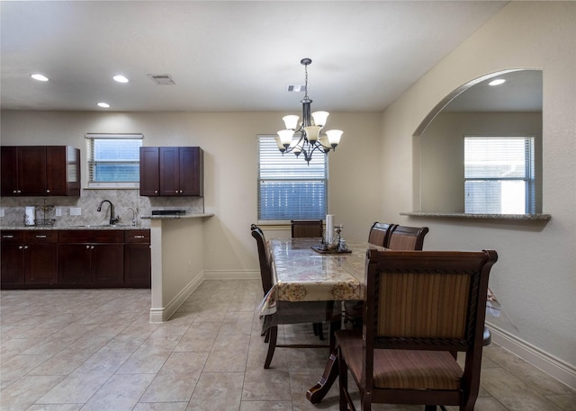 tiled dining area featuring sink and a chandelier