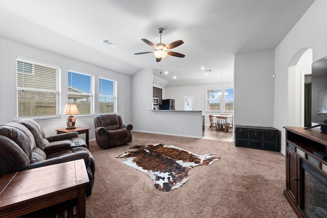 carpeted living room with ceiling fan and vaulted ceiling