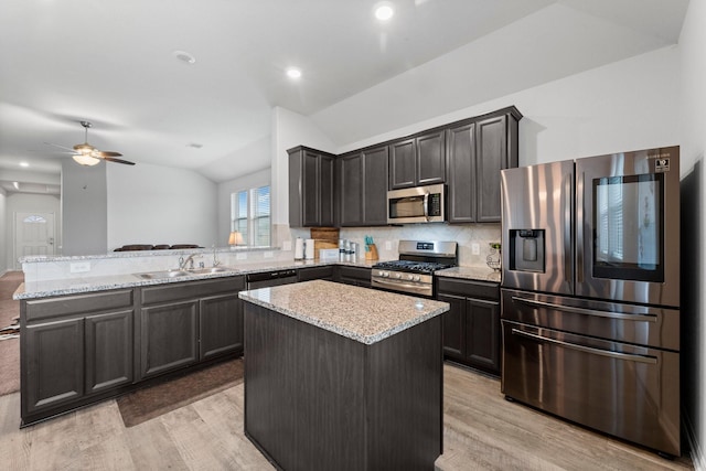 kitchen featuring lofted ceiling, stainless steel appliances, decorative backsplash, and a center island