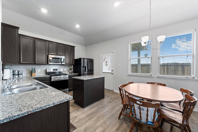 kitchen featuring appliances with stainless steel finishes, hanging light fixtures, a center island, sink, and an inviting chandelier