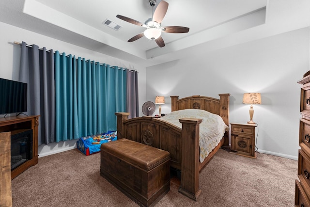 carpeted bedroom with a raised ceiling and ceiling fan