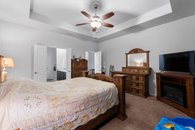 bedroom with ensuite bath, carpet, ceiling fan, and a tray ceiling