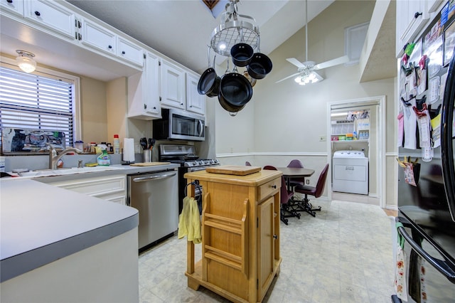 kitchen featuring sink, appliances with stainless steel finishes, white cabinets, washer / clothes dryer, and decorative light fixtures