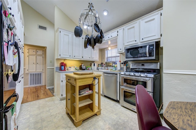 kitchen with lofted ceiling, appliances with stainless steel finishes, an inviting chandelier, hanging light fixtures, and white cabinets