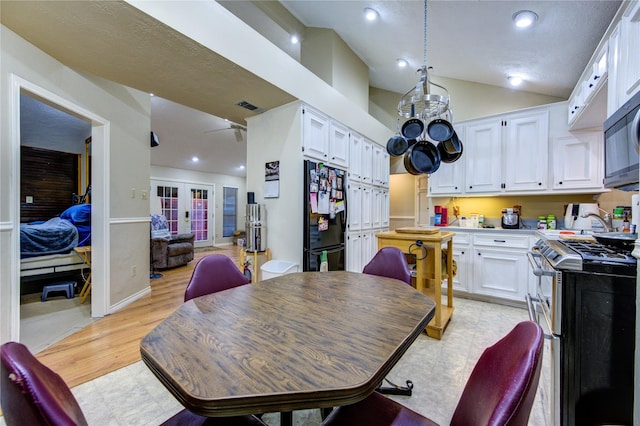 dining area with french doors, light hardwood / wood-style floors, and vaulted ceiling