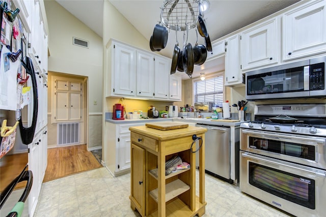 kitchen with vaulted ceiling, white cabinets, and appliances with stainless steel finishes