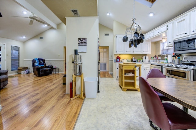 kitchen featuring stainless steel appliances, hanging light fixtures, white cabinets, and lofted ceiling with beams