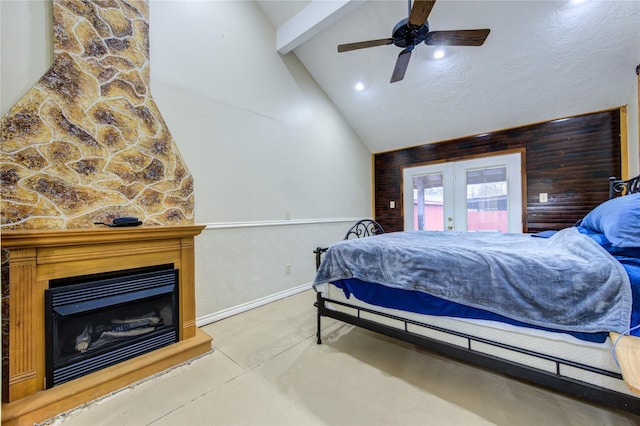 bedroom with french doors, a stone fireplace, concrete flooring, vaulted ceiling with beams, and ceiling fan