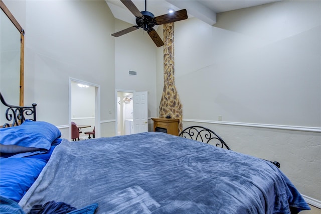 bedroom with beam ceiling, ensuite bathroom, ceiling fan, and a high ceiling