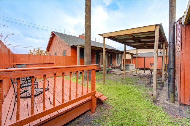 wooden terrace with a hot tub and a lawn