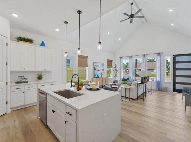 kitchen featuring decorative backsplash, a kitchen island with sink, sink, and white cabinets