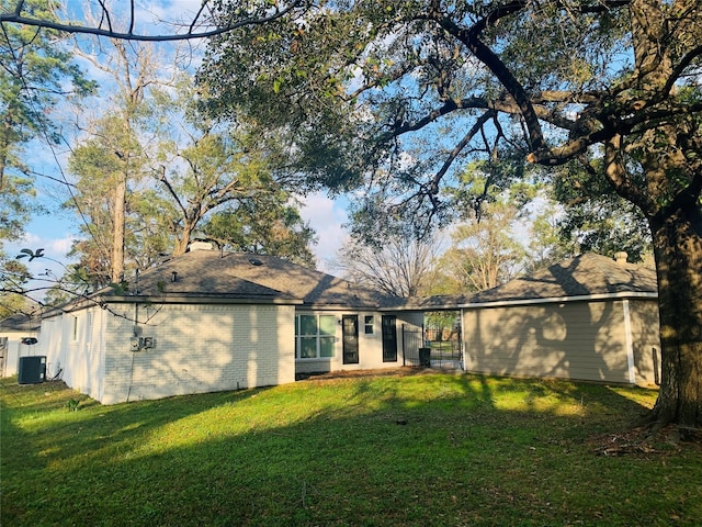 back of house featuring central AC unit and a lawn