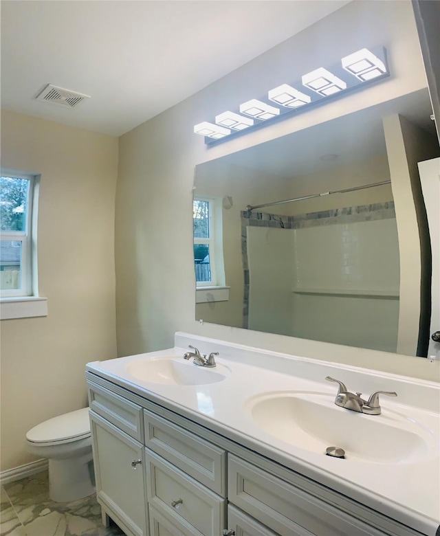 bathroom with vanity, a shower, a wealth of natural light, and toilet