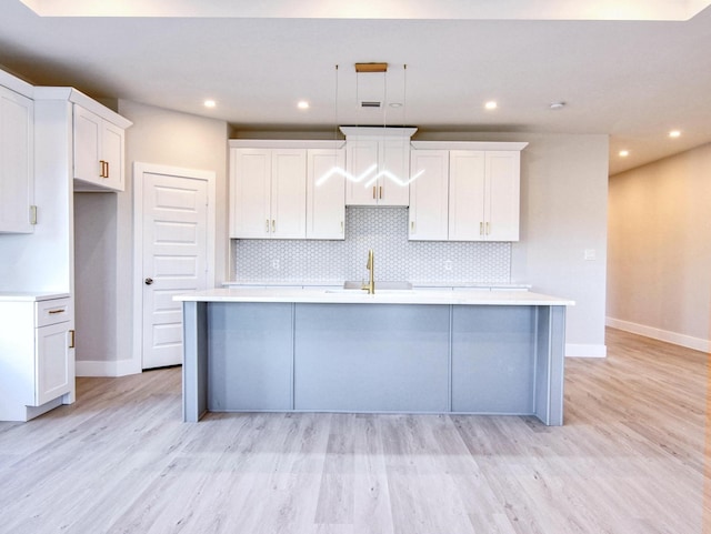 kitchen featuring white cabinetry, sink, a center island with sink, and backsplash