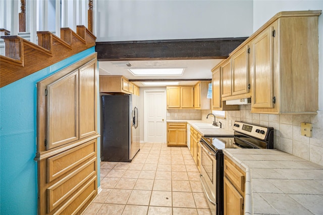 kitchen with appliances with stainless steel finishes, backsplash, sink, beam ceiling, and tile counters