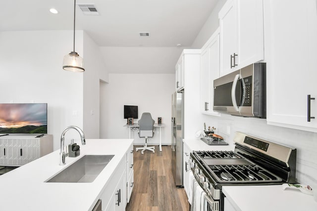 kitchen with white cabinetry, sink, dark hardwood / wood-style floors, pendant lighting, and appliances with stainless steel finishes