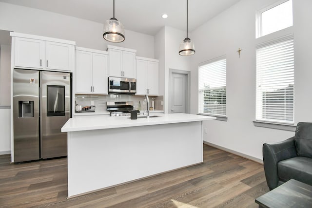 kitchen with a center island with sink, decorative light fixtures, white cabinets, and stainless steel appliances