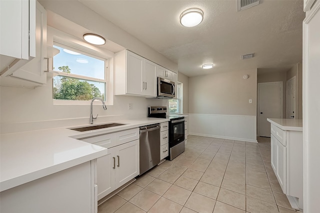 kitchen with light tile patterned floors, white cabinetry, sink, and appliances with stainless steel finishes