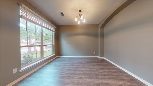 spare room with plenty of natural light, a chandelier, and hardwood / wood-style flooring