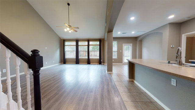 unfurnished living room with ceiling fan, sink, and light hardwood / wood-style flooring