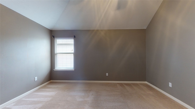 spare room featuring light colored carpet and vaulted ceiling