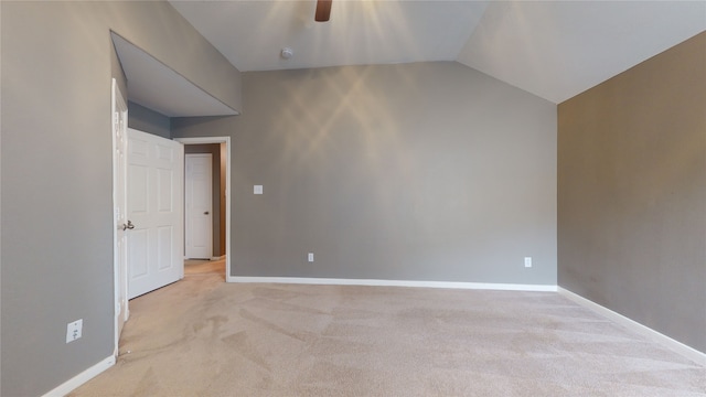 spare room featuring light carpet, vaulted ceiling, and ceiling fan